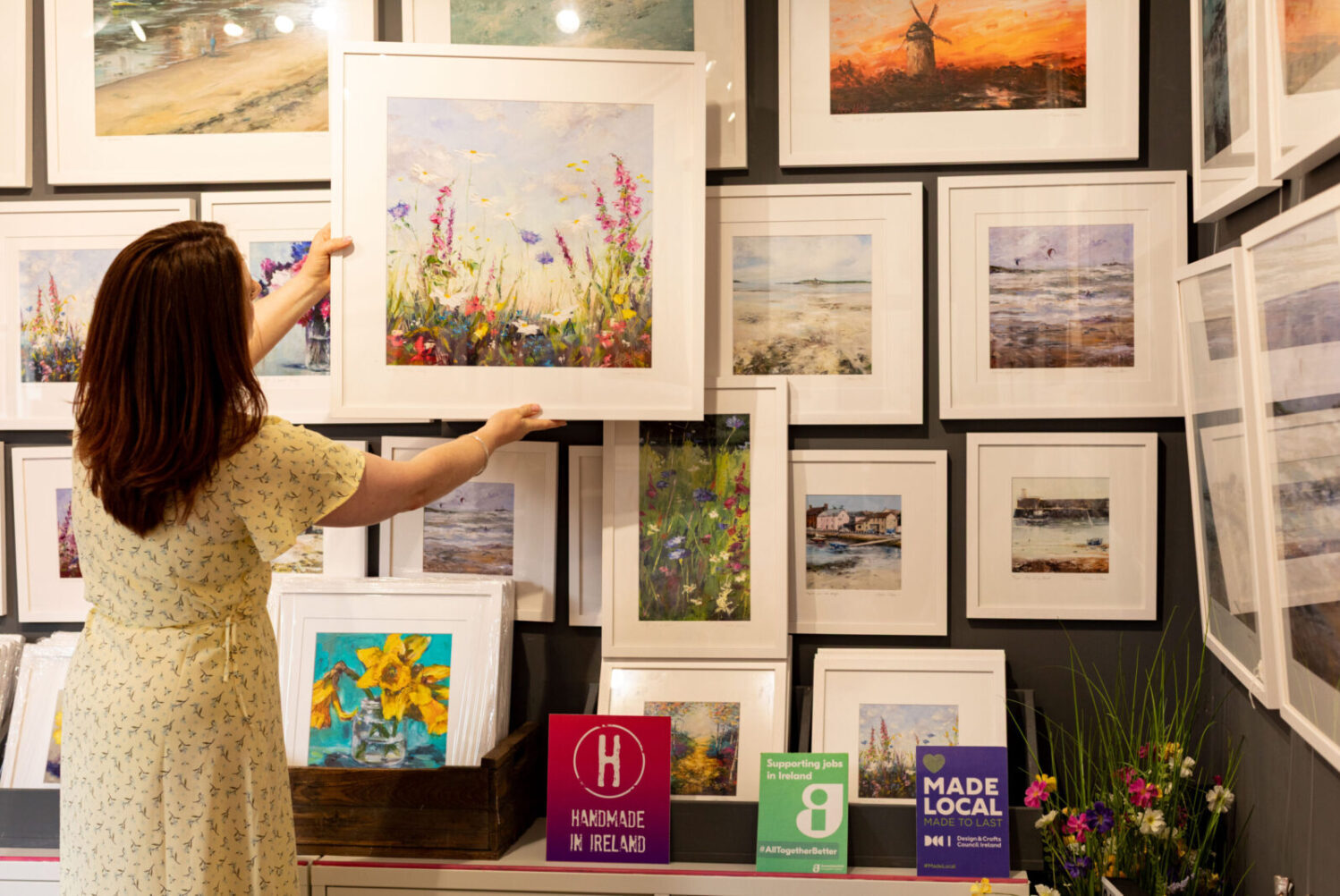 Claire holding large print, with Made Irish and Guaranteed irish signage